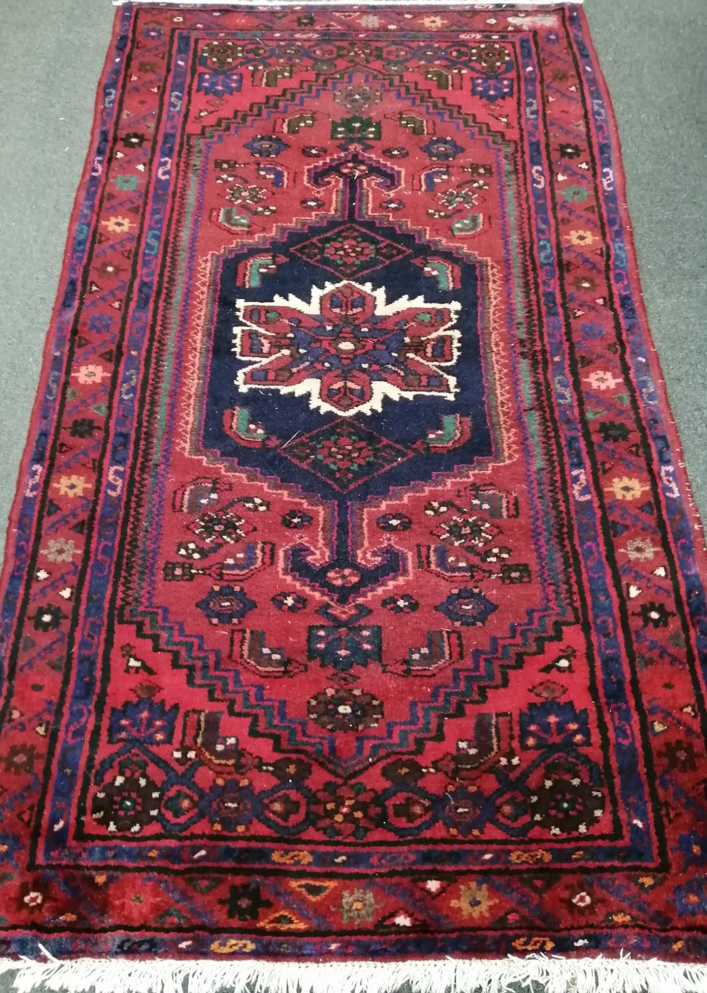 A Caucasian style burgundy ground rug, 200 x 110cm